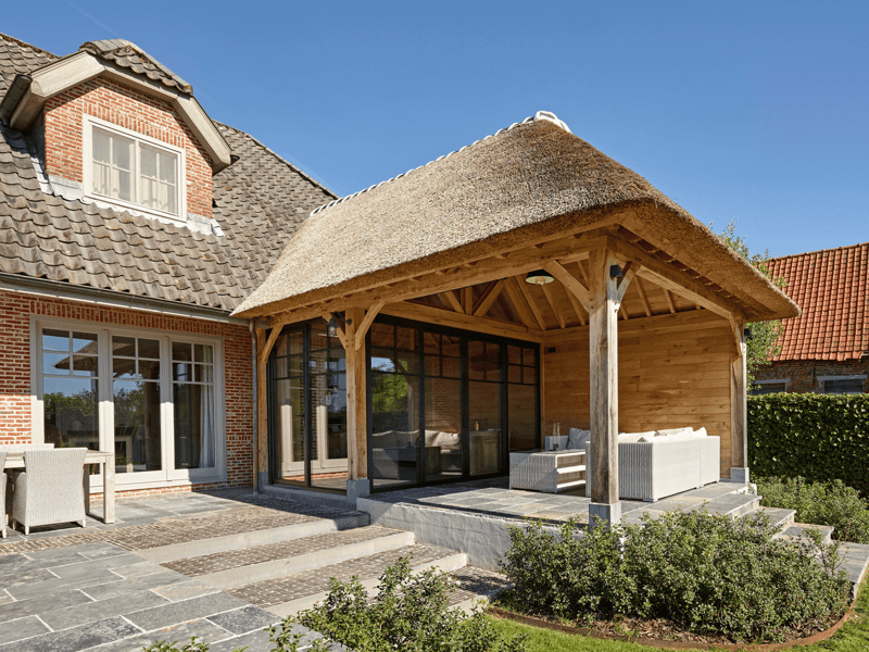 Eiken aanbouw en overdekt terras met rieten dak in Brakel