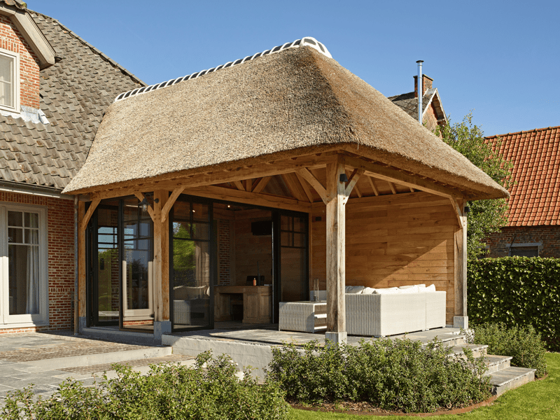 Eiken aanbouw en overdekt terras met rieten dak in Brakel